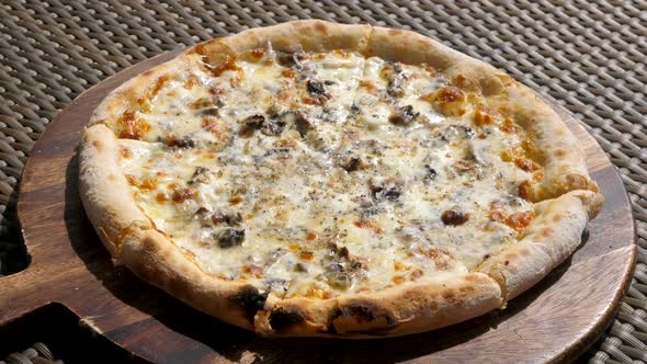 Closeup of Baked Truffle Pizza on Wooden Plate in Outdoor Cafe at Hot Sunny Day