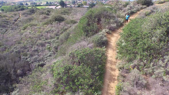 Aerial shot of a young man trail running on a scenic hiking trail