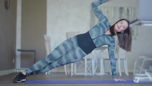 Wide Shot of Slim Caucasian Woman in Sportswear Working Out on Exercise Mat. Portrait of Young