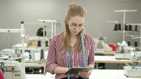 Fashion designer uses tablet in clothing factory for creative production