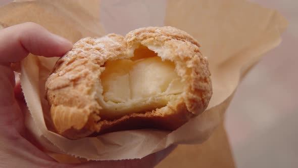 Caramel Profiterole in the Hand of a Person Closeup Street Food Urban Pastries