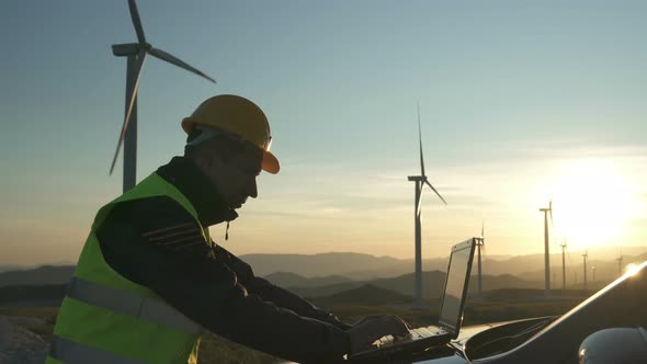 Technician Engineer in Wind Turbine Power Generator Station Checks the Status of the Turbines Using