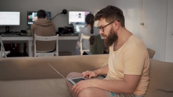 Freelancer Man Is Working with Laptop Sitting on a Couch in a Coworking Space