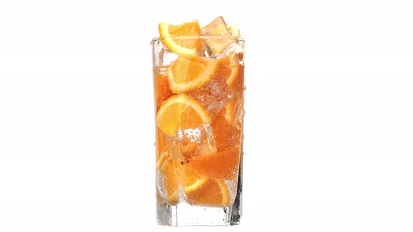 Rotation Glass Cold Refreshment Sweet Water Ripe Orange Slice and Ice Cubes Slow Motion Isolated