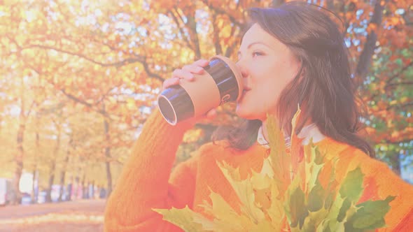 Happy Smiling Woman with Autumn Leaves Drinking Caffee in Fall Park