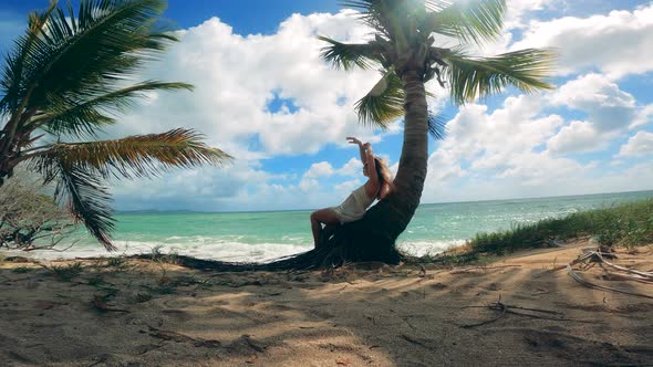 One Woman Rests on a Palm Tree Near Ocean.