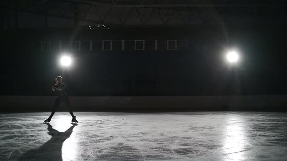 Young Female Figure Skater is Wearing Black Sportswear for Workout is Skating on Ice Rink Alone at