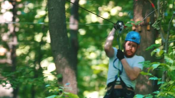 A Man in Helmet Having a Rope Adventure in the Forest with Full Insurance - Coming Down Using His