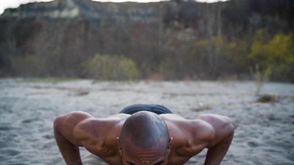 Attractive and athletic man doing push-ups on a beach in slow motion