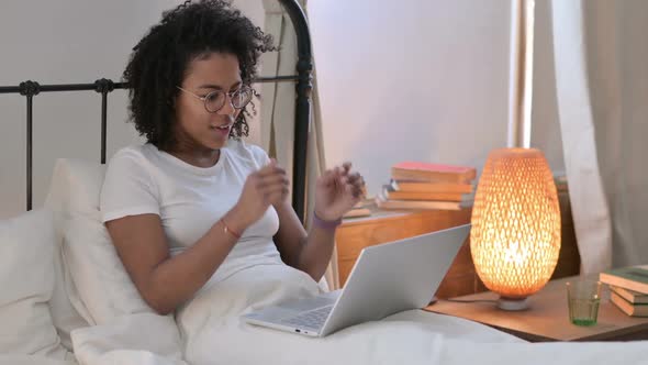 Attractive African Woman Celebrating on Laptop in Bed
