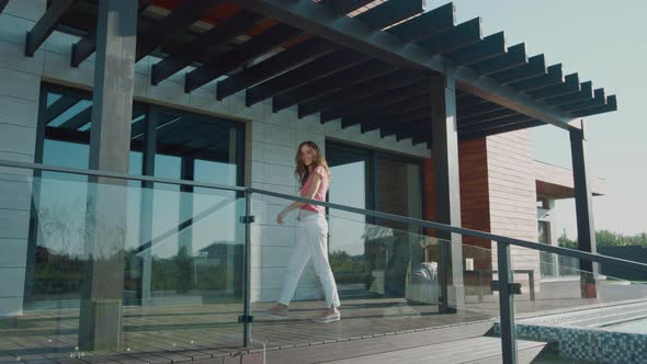 Happy Woman Waving Hand on Luxury House. Welcome Home in Mansion