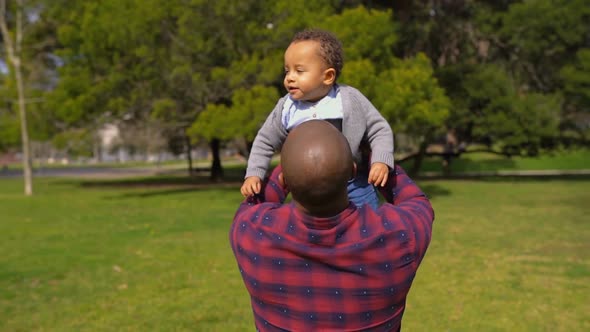 Father Holding Little Mixed-race Boy in Arms, Spinning Him Around
