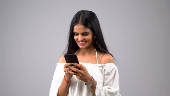 Happy Indian girl using smartphone