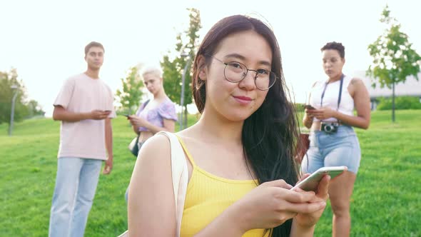 Young happy asiatic woman outdoor using smartphone