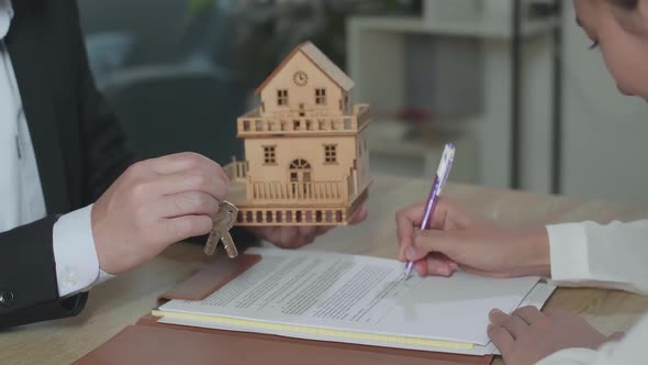 Real Estate Agent Giving The House Model And Keys To A Woman After Signing On House Purchase