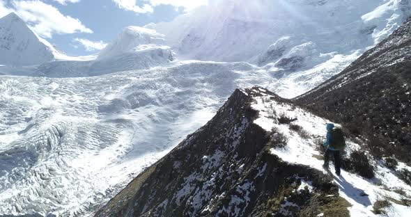 Woman backpacker climbing up high altitude mountains in winter 