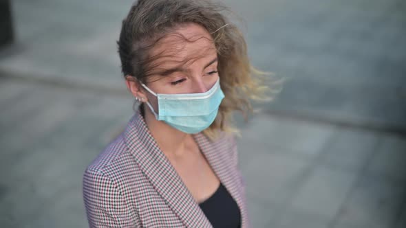 young business woman wearing a medical mask, her hair is blown up by the wind