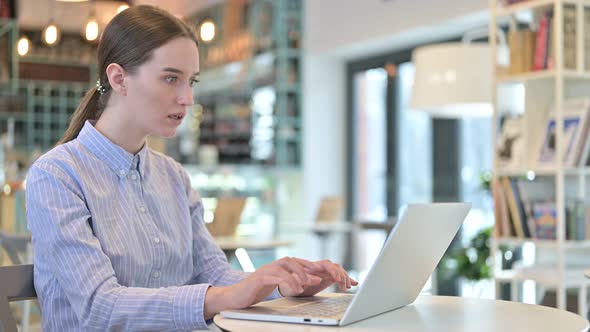 Loss on Laptop By Young Businesswoman in Cafe