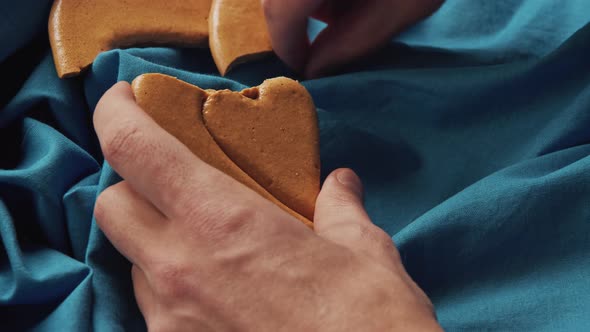 Men's Hands Break Sugar Cookies Candy in the Shape of a Heart