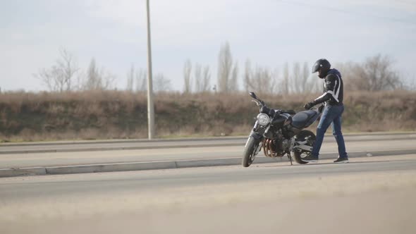 Young Attractive Man Motorcyclist with Black Helmet and Sport Motorcycle on Street