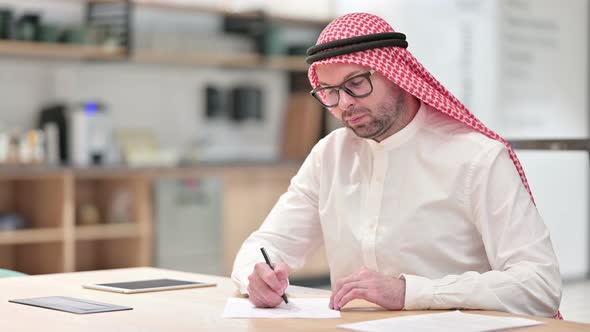 Young Arab Businessman Writing on Paper in Office 