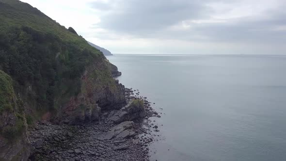 Aerial tracking upwards above the rugged cliffs of Exmoor looking west at the Valley of rocks. Devon