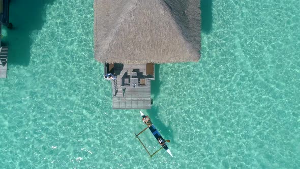 Aerial drone view of a man and woman couple in an overwater bungalow on Bora Bora tropical island