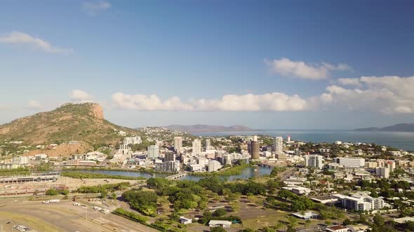 Drone moves right to left and slowly pans right while overlooking Townsville city and Castle Hill on