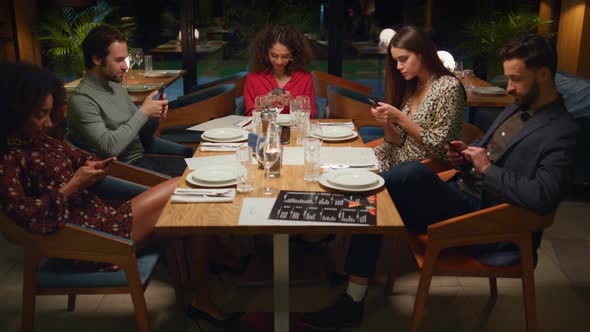 Friends Table Reading Mobile Phone Browsing Internet Social Media in Restaurant