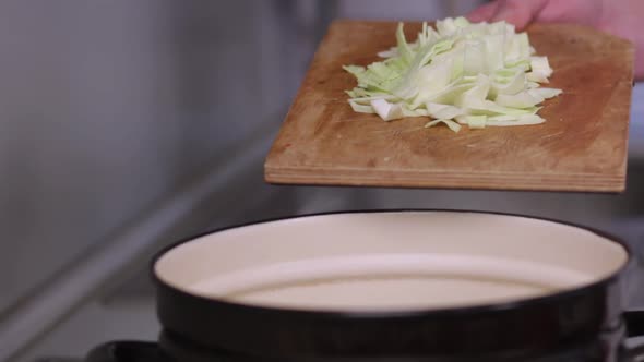 the chef pours cabbage into a healthy vegetable soup with milk