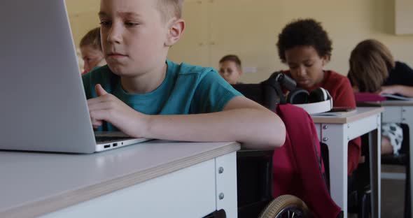 Physically challenged boy using laptop in the class