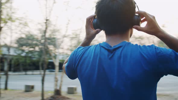 A sporty Asian man wearing headphones ready for running exercise and jogging at the park.