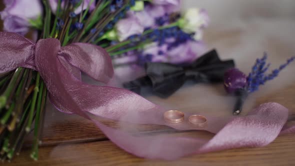 Rings in smoke on table close up. Groom accessory like boutonniere, flowers and butterfly indoors