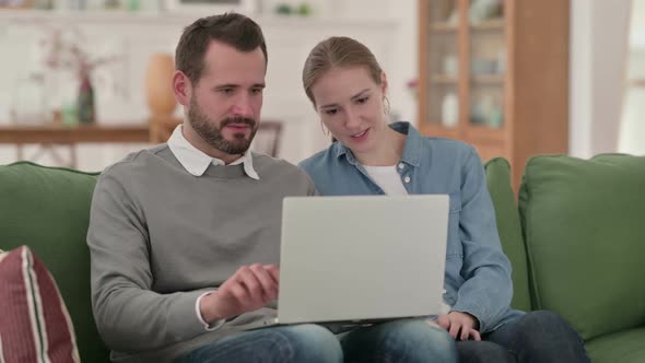 Couple Excited While Working on Laptop at Home