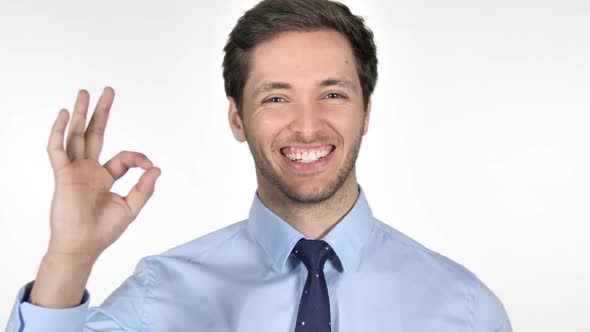 Gesture of Okay By Young Businessman on White Background