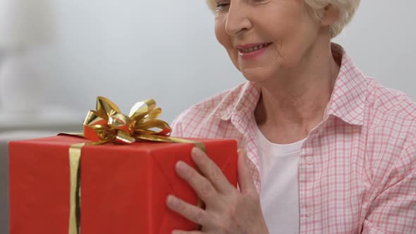 Happy Elderly Woman With Red Gift Box Smiling at Camera, Anniversary Celebration