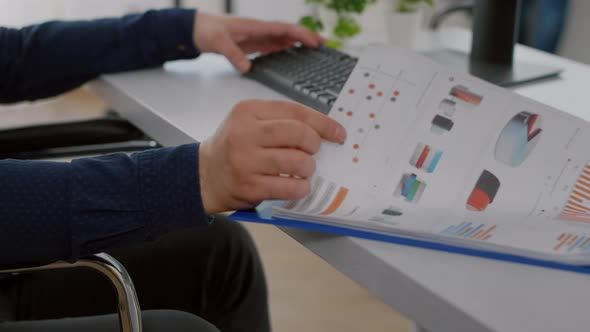 Close Up of Handicapped Entrepreneur with Protective Face Mask Analysing Graphs