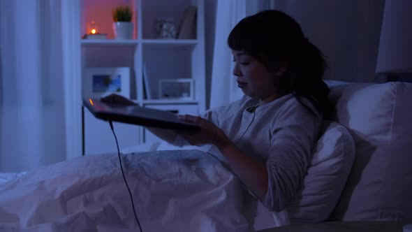 Woman with Laptop in Bed at Home at Night