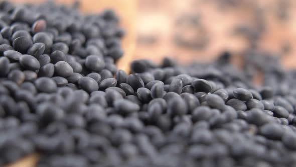 Beluga black lentils fall in slow motion in a heap in a wooden dish