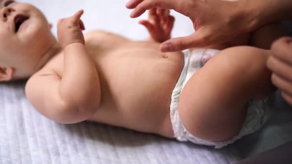Female Hands Massage the Tummy of a Laughing Baby