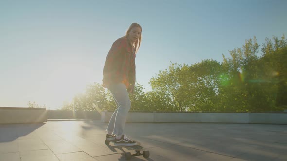 Beautiful Young Female Skater Riding on Longboard at Daybreak