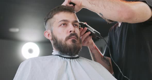 View From the Bottom of Face of Young Bearded Man Who is Sitting on the Barber's Chair Facing the