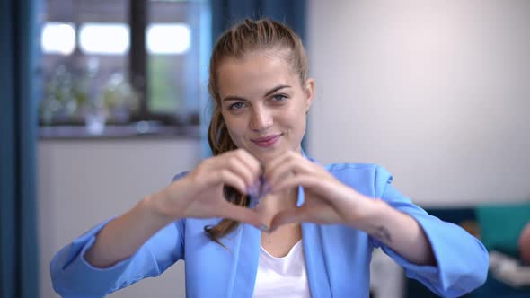 Elegant Charming Caucasian Woman Gesturing Heart Shape with Hands Smiling Looking at Camera