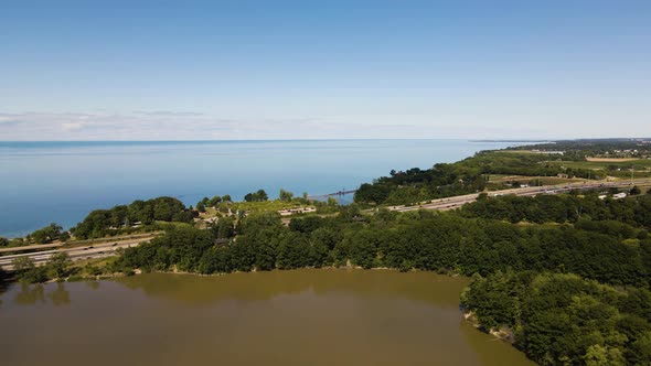 Aerial view of a cars driving on a highway on the shore of Lake Ontario and Sixteen Mile Pond. Aeria