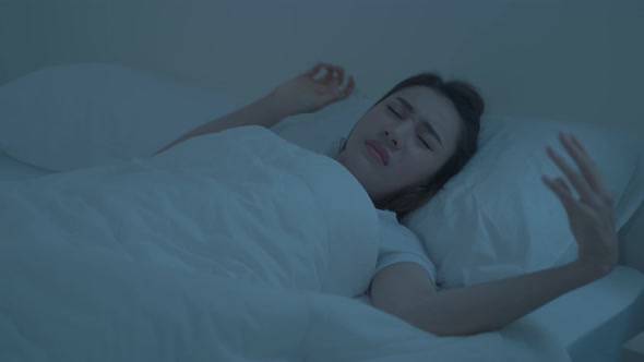 Asian beautiful frustrated girl in pajamas lying down on bed in dark night sleep in bedroom in house