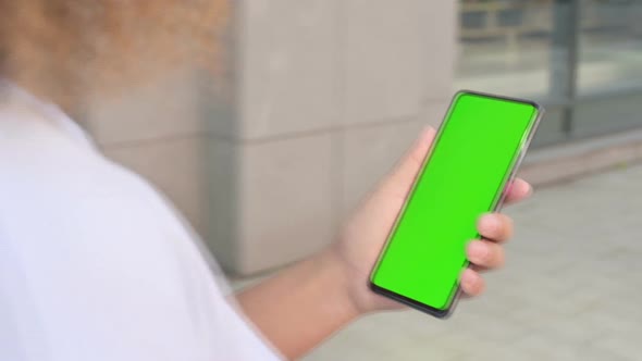 African Woman Looking at Smartphone with Green Chroma Screen