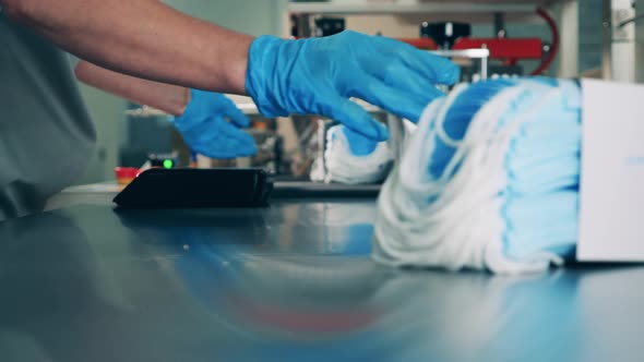 Factory Worker Is Loading New Medical Masks Into the Conveyor