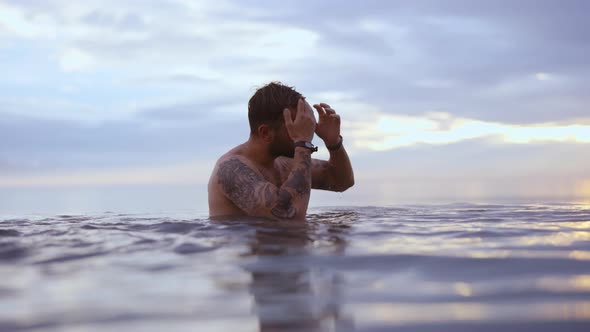 Tattooed Male Model Swimming in Water With the Backdrop