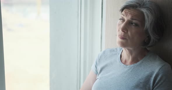 An Elderly Thoughtful Disabled Senior Woman Looking Out the Window From the Hospital and Smiling