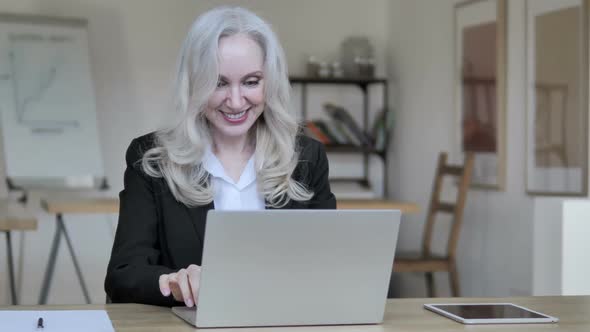 Senior Businesswoman Celebrating Success on Laptop